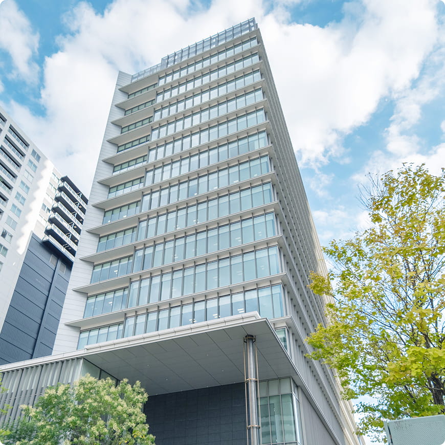 青空の下にそびえ立つ、ガラス張りの近代的な高層ビル