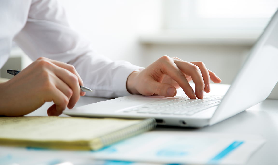 デスクで資料を広げながらパソコンを使い研修内容を学ぶ社員の手元