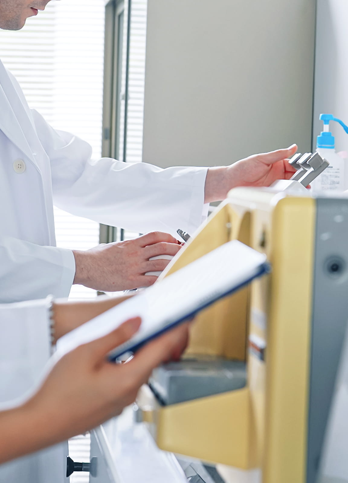 研究機器を操作する白衣の研究員の手元。